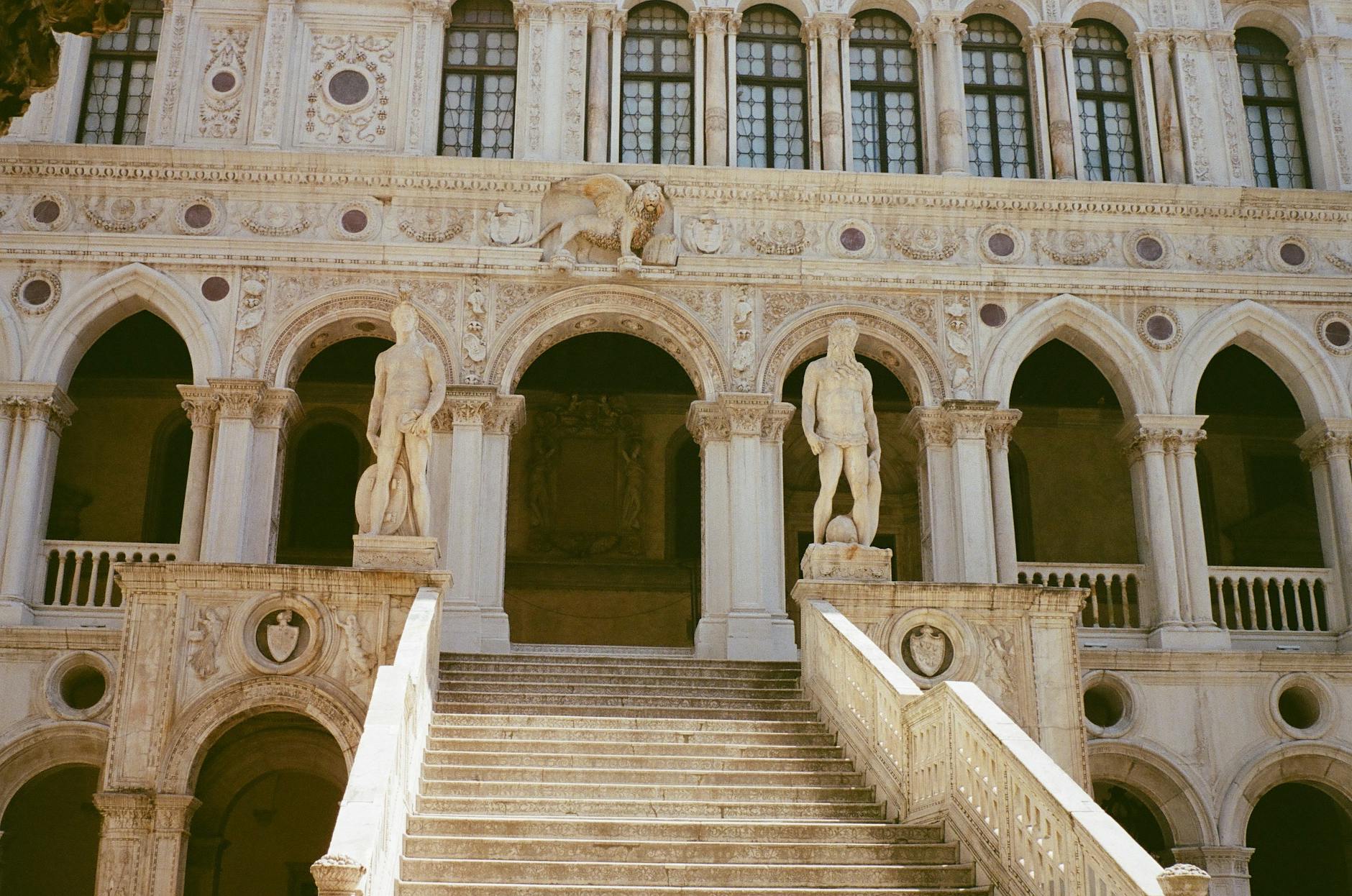 Stone staircase leading to an ornate building entrance with statues and arches