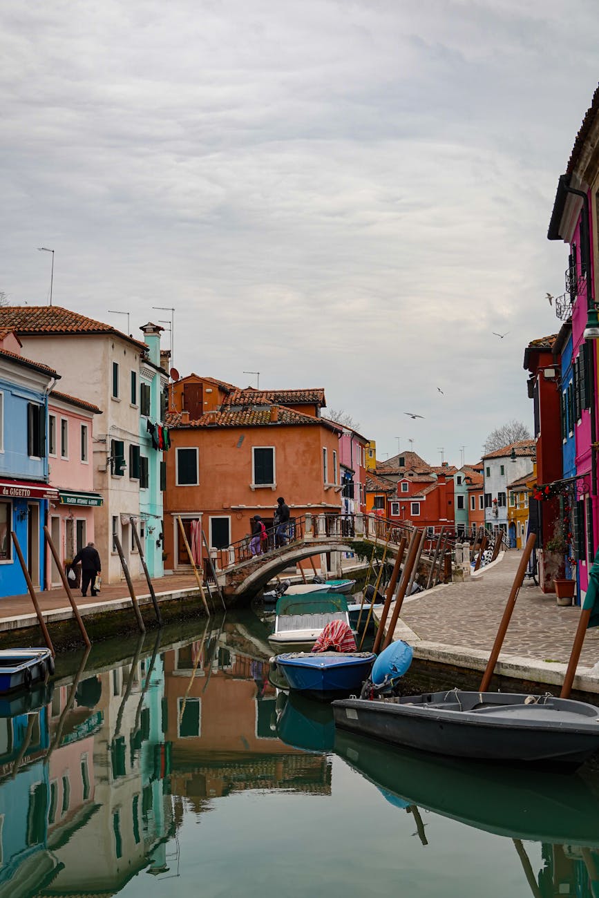 Canal with boats and colorful buildings on both sides connected by a small arched pedestrian bridge