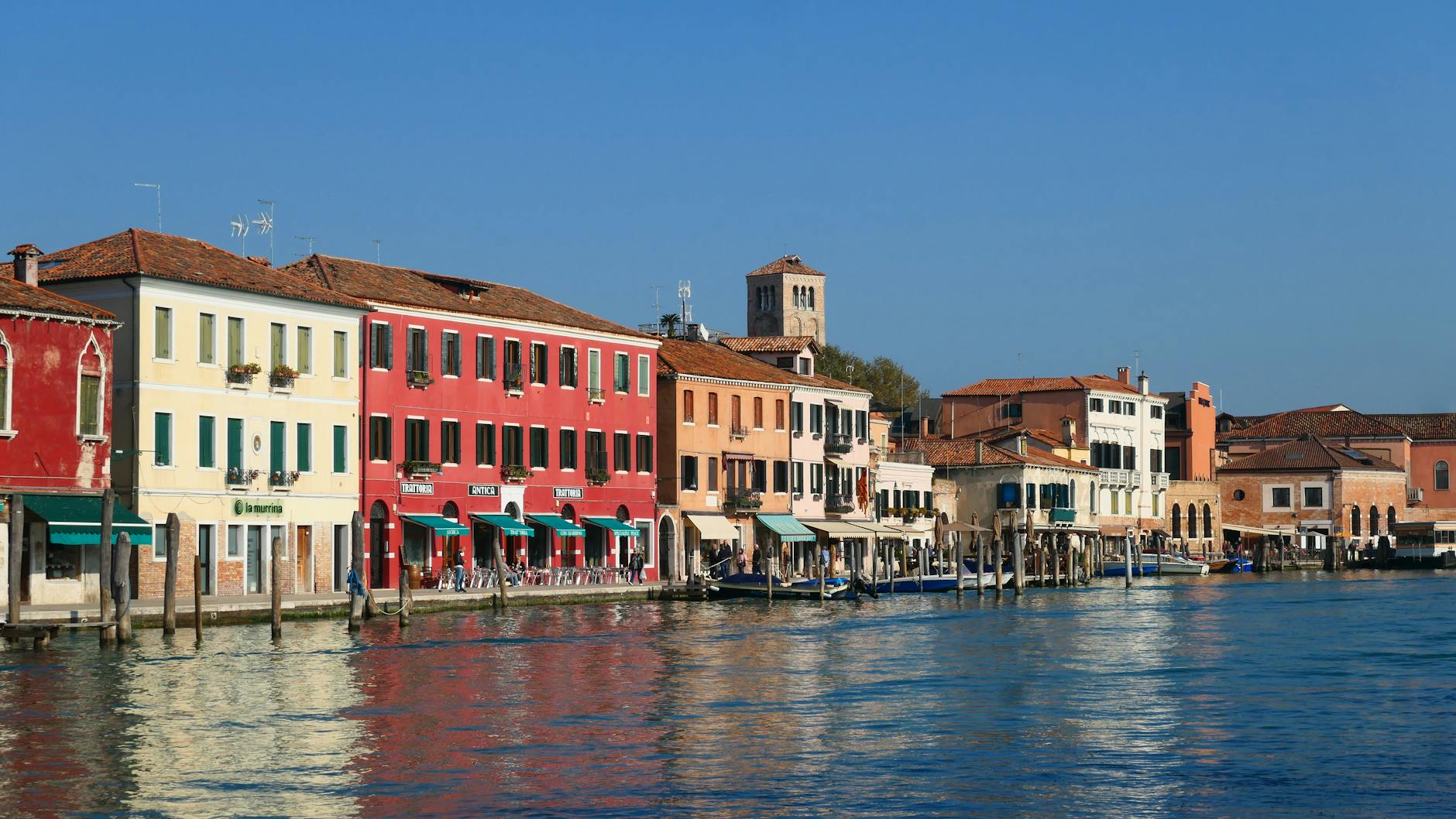 Colorful buildings along a waterfront with boats docked and clear blue sky