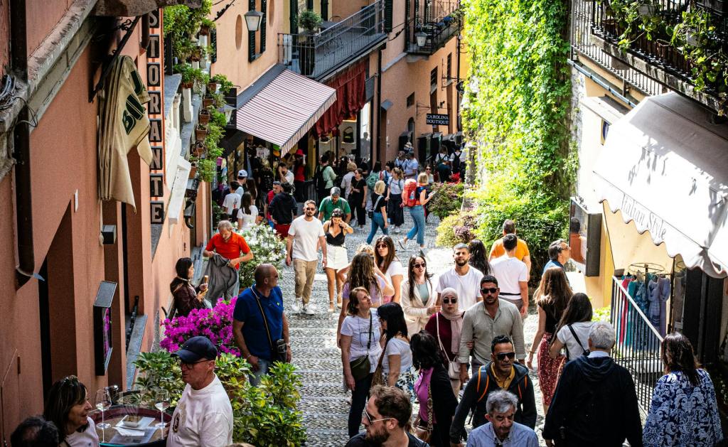 A bustling pedestrian street filled with people, lined with shops and restaurants, adorned with vibrant flowers and greenery.