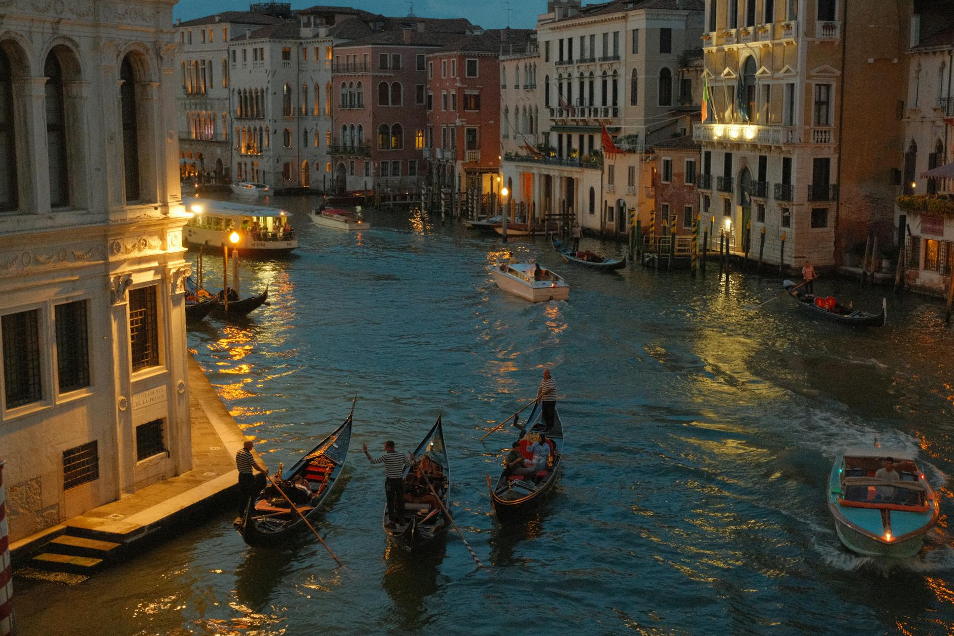 Evening scene of Venice canal with gondolas and boats near illuminated historic buildings