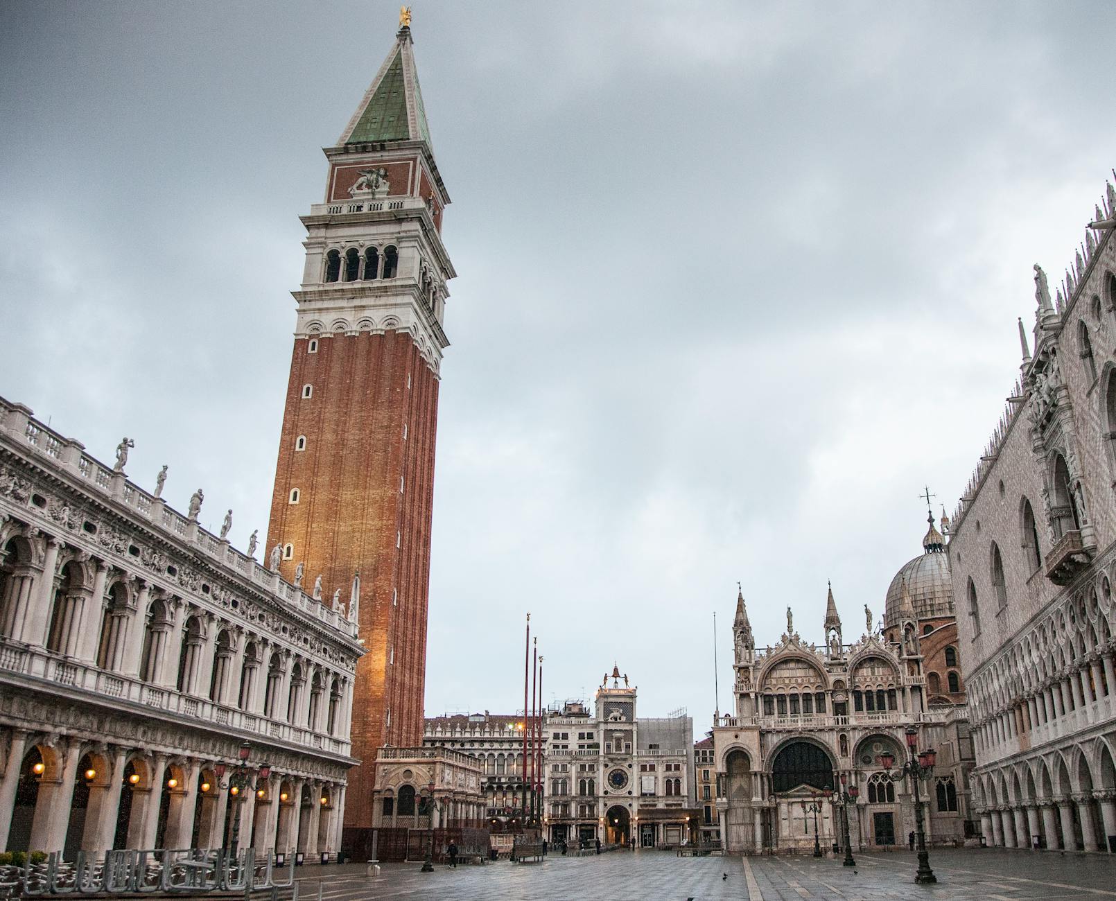 Tall Campanile bell tower and historic buildings in Venice's Piazza San Marco under cloudy sky