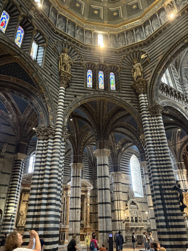 Interior view of a grand cathedral featuring prominent black and white striped columns, stained glass windows, and intricate detailing on the arches and ceiling.