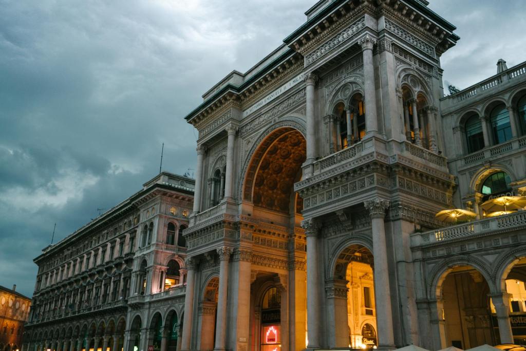 An ornate historic building with a prominent archway, illuminated at dusk, showcasing intricate architectural details in Florence, Italy.